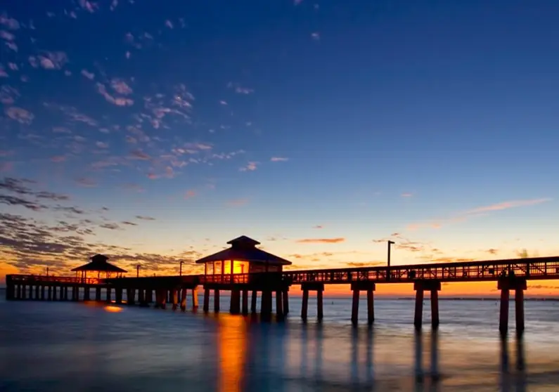 Fishing pier silhouetted at sunset in Fort Myers Beach, FL