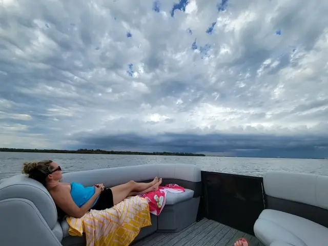 Guest relaxing on a pontoon as storm clouds build over the water in Southwest Florida