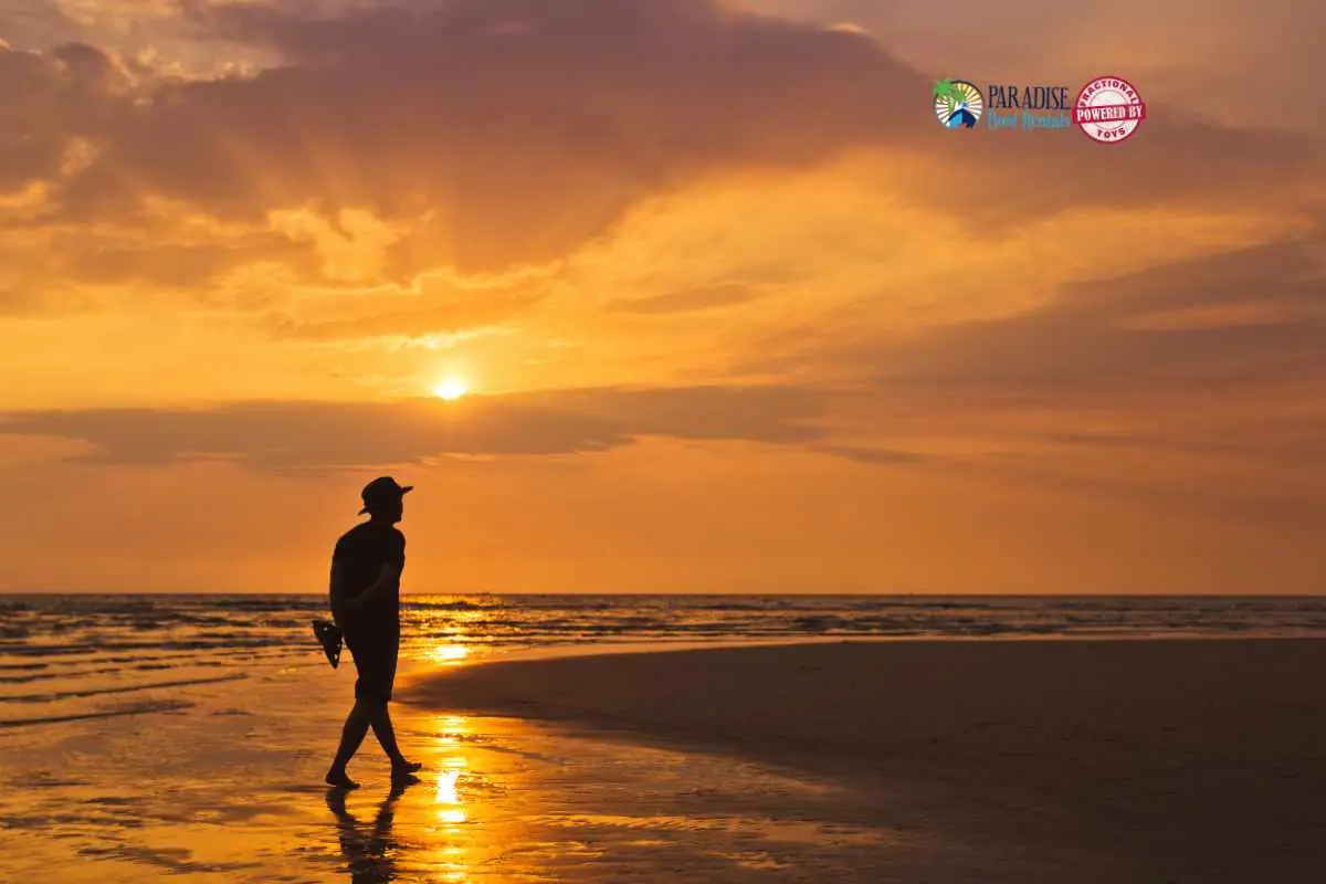 Man walking along the beach at sunset