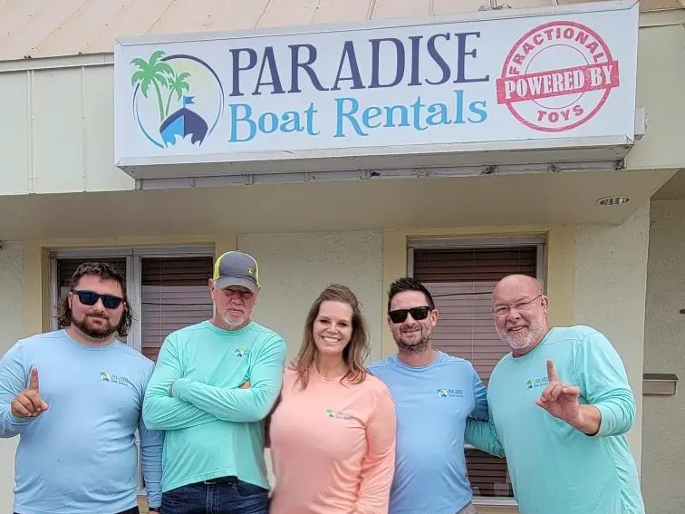 The Paradise Boat Rentals team and shop dog under our storefront sign in Cape Coral, FL