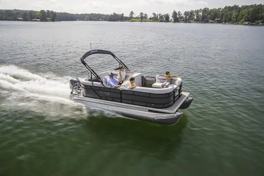 Pontoon boat cruising past a wooded shoreline for rent in Cape Coral, FL