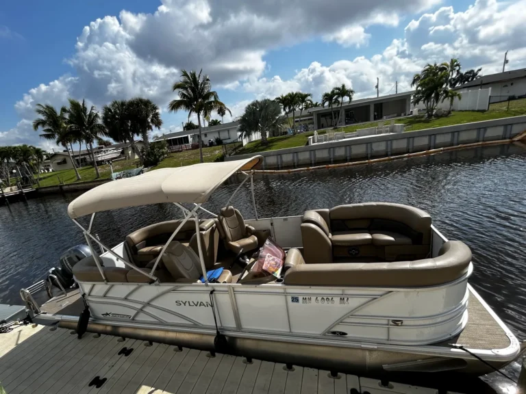 Sylvan X-Series Tritoon rental boat with a tan bimini top at the dock